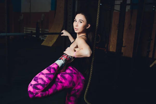 Seorang gadis olahraga yang cantik melatih bisep dengan tongkat di tangannya di gym . — Stok Foto