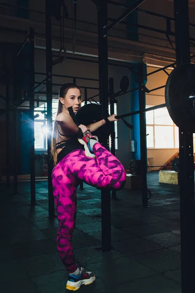 Piękna dziewczyna sportu trenuje biceps z prętem w rękach w siłowni. — Zdjęcie stockowe