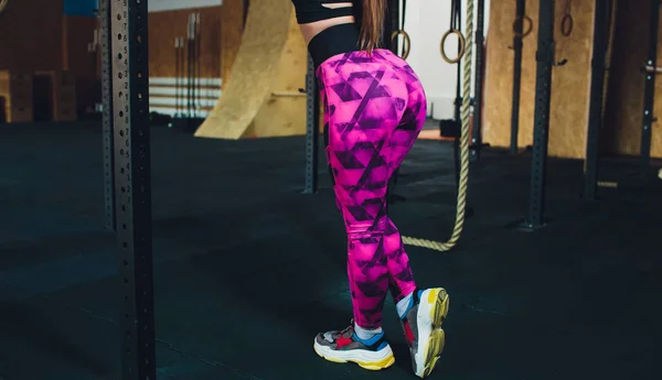 Uma bela menina de esportes treina um bíceps com uma vara em suas mãos no ginásio . — Fotografia de Stock