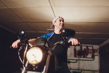 Adam bisikleti onariyor. Onun garaj yakınında motosiklet tamir emin genç adam.