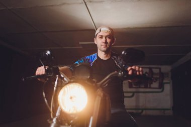Adam bisikleti onariyor. Onun garaj yakınında motosiklet tamir emin genç adam.