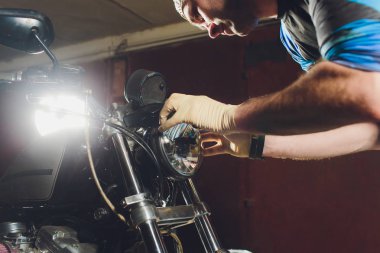 Adam bisikleti onariyor. Onun garajına yakın motosiklet tamir emin genç adam. Far içinde yedek lamba