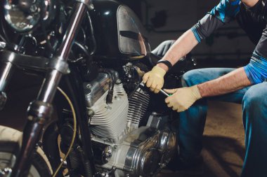 Adam bisikleti onariyor. Onun garaj yakınında motosiklet tamir emin genç adam.