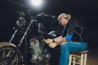 Adam bisikleti onariyor. Onun garaj yakınında motosiklet tamir emin genç adam.
