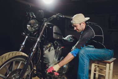 Adam bisikleti onariyor. Onun garaj yakınında motosiklet tamir emin genç adam.