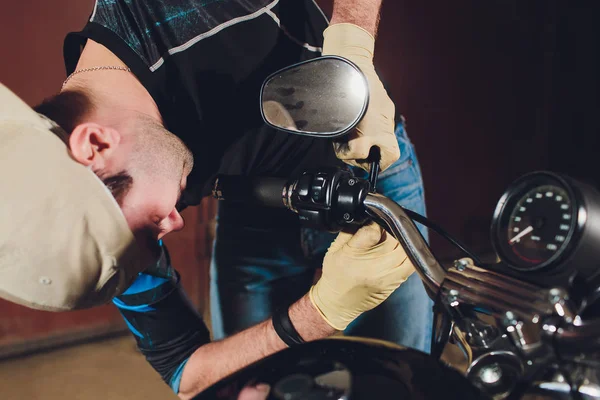 Hombre arreglando bicicleta. Joven confiado reparando motocicletas cerca de su garaje. ajuste del espejo retrovisor . — Foto de Stock