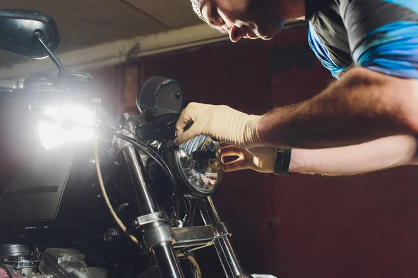 Adam bisikleti onariyor. Onun garajına yakın motosiklet tamir emin genç adam. Far içinde yedek lamba