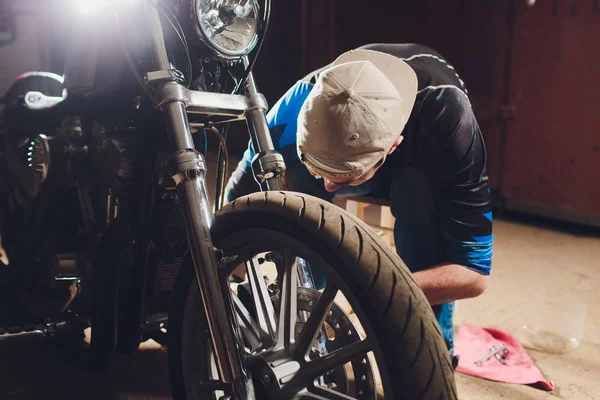 Hombre arreglando bicicleta. Joven confiado reparando motocicleta cerca de su garaje . — Foto de Stock