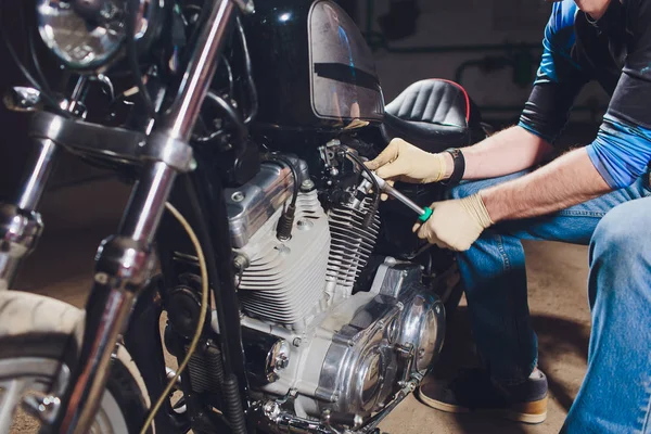 Adam bisikleti onariyor. Onun garaj yakınında motosiklet tamir emin genç adam.