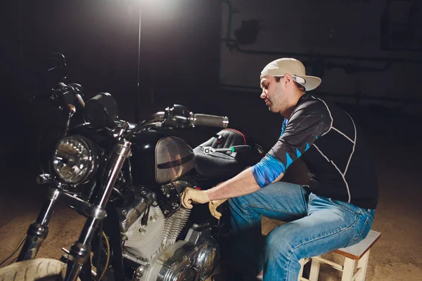Adam bisikleti onariyor. Onun garaj yakınında motosiklet tamir emin genç adam.