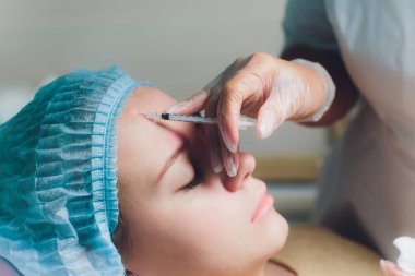 Orta yaş kadın alnında bir klinik cerrahi oda ameliyathane ifade kırışıklıkların kaldırmak için kaşları arasında arka plan Beautify enjeksiyon kaldırma yüz yüz yaşlanma kavramı anti için dolgu veren doktor