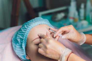 Orta yaş kadın alnında bir klinik cerrahi oda ameliyathane ifade kırışıklıkların kaldırmak için kaşları arasında arka plan Beautify enjeksiyon kaldırma yüz yüz yaşlanma kavramı anti için dolgu veren doktor