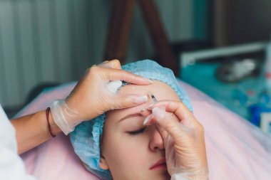 Orta yaş kadın alnında bir klinik cerrahi oda ameliyathane ifade kırışıklıkların kaldırmak için kaşları arasında arka plan Beautify enjeksiyon kaldırma yüz yüz yaşlanma kavramı anti için dolgu veren doktor