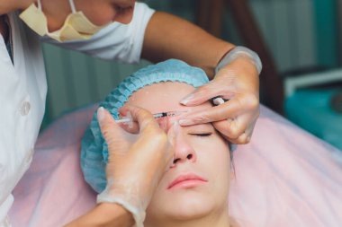 Orta yaş kadın alnında bir klinik cerrahi oda ameliyathane ifade kırışıklıkların kaldırmak için kaşları arasında arka plan Beautify enjeksiyon kaldırma yüz yüz yaşlanma kavramı anti için dolgu veren doktor