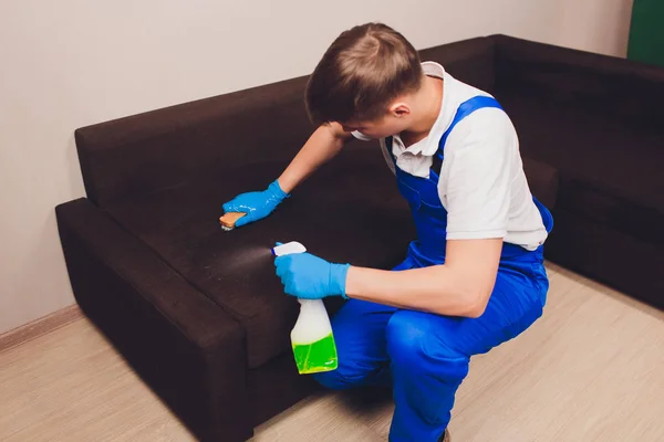 Περικομμένη εικόνα. Καθαρισμός έννοια. Αρσενική χέρι σε προστατευτικά γάντια καθαρισμού καναπέ-κρεβάτι στο δωμάτιο. — Φωτογραφία Αρχείου