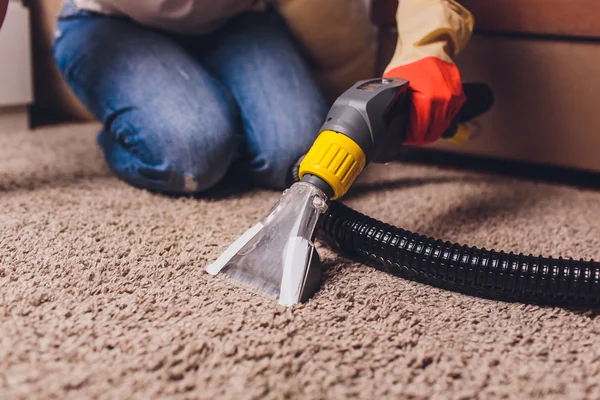 Mujer eliminando la suciedad de la alfombra con aspiradora en la habitación . —  Fotos de Stock