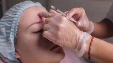 Orta yaş kadın alnında bir klinik cerrahi oda ameliyathane ifade kırışıklıkların kaldırmak için kaşları arasında arka plan Beautify enjeksiyon kaldırma yüz yüz yaşlanma kavramı anti için dolgu veren doktor