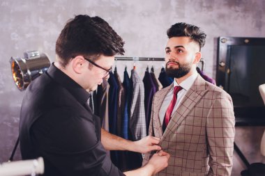 Terzide dikiş dikmek için ölçü alan olgun profesyonel bir terzi. Ölçüm bandı olan adam meşgul. Özel Yapımlı Kumaş Konsepti.