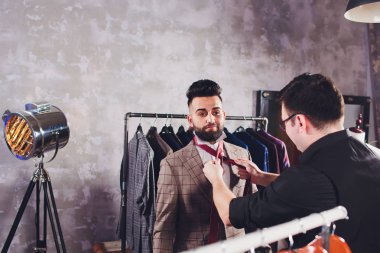 Terzide dikiş dikmek için ölçü alan olgun profesyonel bir terzi. Ölçüm bandı olan adam meşgul. Özel Yapımlı Kumaş Konsepti.