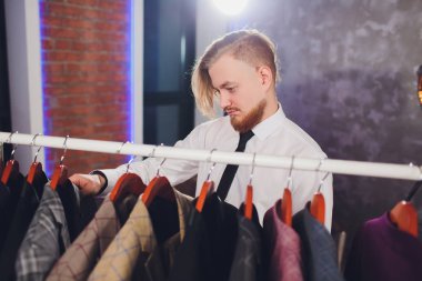 Erkek müşterinin portresi alışveriş merkezinde klasik ceket seçiyor..