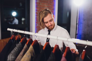 Erkek müşterinin portresi alışveriş merkezinde klasik ceket seçiyor..
