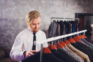 Erkek müşterinin portresi alışveriş merkezinde klasik ceket seçiyor..