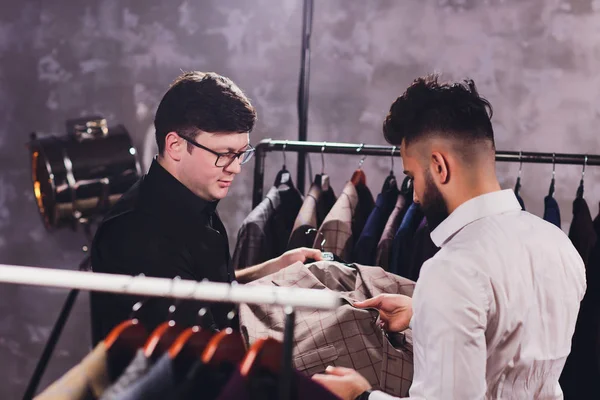 ショッピングモールで男性の顧客は、ビジネスの服を試して、クライアントにお手伝いショップアシスタント. — ストック写真
