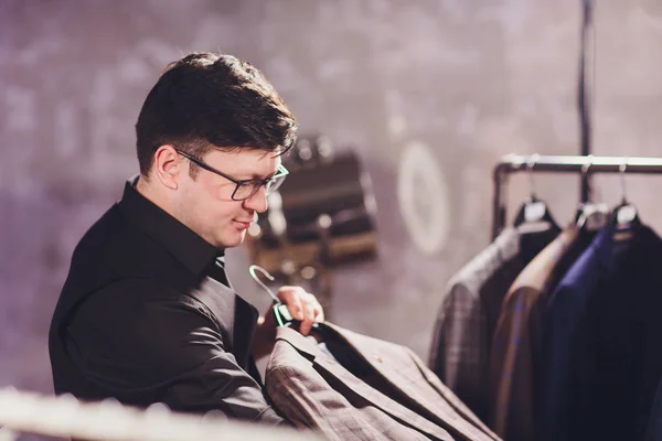 Mężczyzna klienta w centrum handlowym próbuje ubrania biznesowe, asystent sklepu pomagając klientowi. — Zdjęcie stockowe