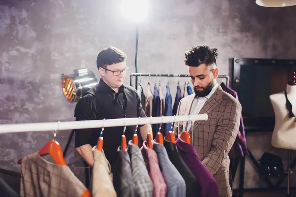 Αρσενικό πελάτης στο εμπορικό κέντρο προσπαθεί επαγγελματικά ρούχα, βοηθός καταστήματος βοηθώντας τον πελάτη. — Φωτογραφία Αρχείου