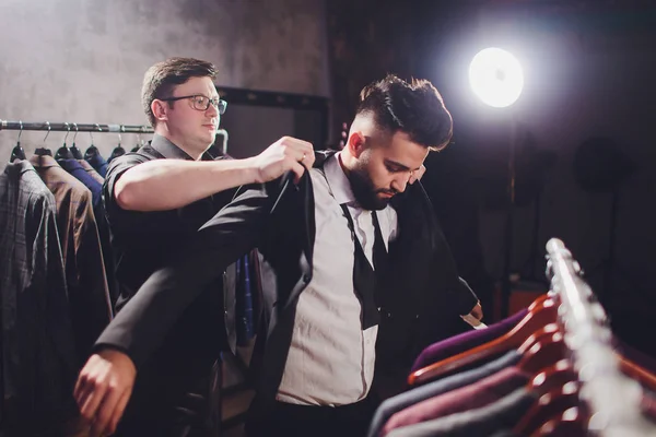 Cliente masculino en el centro comercial probando ropa de negocios, asistente de tienda ayudando al cliente . — Foto de Stock
