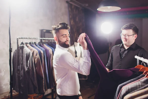 Мужчина в торговом центре пробует деловую одежду, помощник продавца помогает клиенту . — стоковое фото
