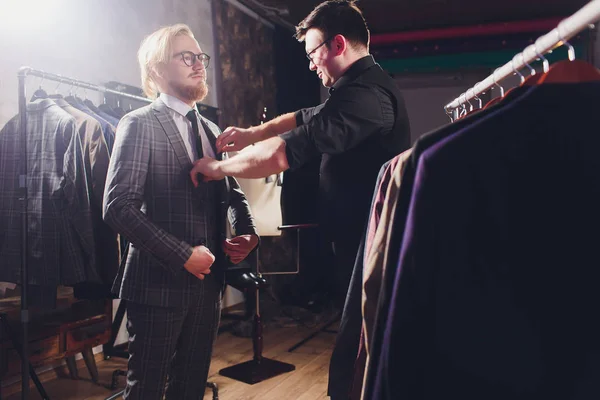 Ώριμος επαγγελματίας ράφτης λαμβάνοντας μετρήσεις για το ράψιμο κοστούμι στο κατάστημα ράφτες. Άνθρωπος με μεζούρα απασχολημένος. Αποκλειστική επί παραγγελία έννοια πανιού. — Φωτογραφία Αρχείου
