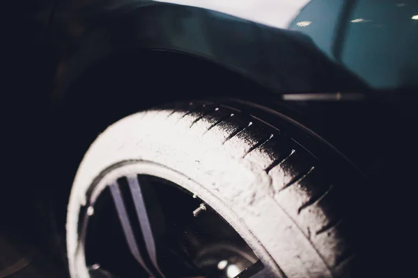 Уход за автомобилем или процесс детализации автомобиля. Использовать черную губку для мытья шины. черная резина . — стоковое фото