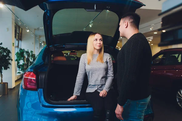 Tomando a decisão deles. Belo casal amoroso sentado em um carro novo juntos na concessionária homem bonito e sua namorada amorosa escolher um carro juntos veículo consumismo . — Fotografia de Stock