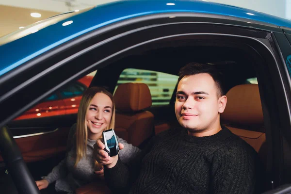 Tomando a decisão deles. Belo casal amoroso sentado em um carro novo juntos na concessionária homem bonito e sua namorada amorosa escolher um carro juntos veículo consumismo . — Fotografia de Stock