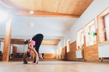 Ön viraj egzersiz, diz, uttanasana poz, kafasına çalışma dışarı duran pratik yoga, genç çekici sportif kadın giyim spor giyim, beyaz loft studio arka plan, tam uzunlukta, yan görünüm