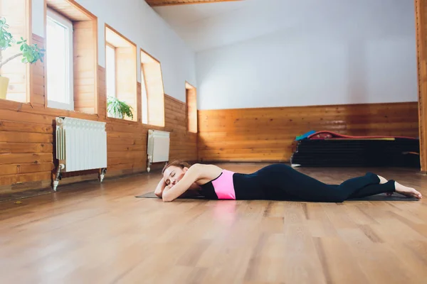 Retrato del cuerpo positivo linda mujer obesa acostada en la esterilla de yoga en el estudio de fitness después de hacer ejercicio y sonreír felizmente a la luz del sol . — Foto de Stock