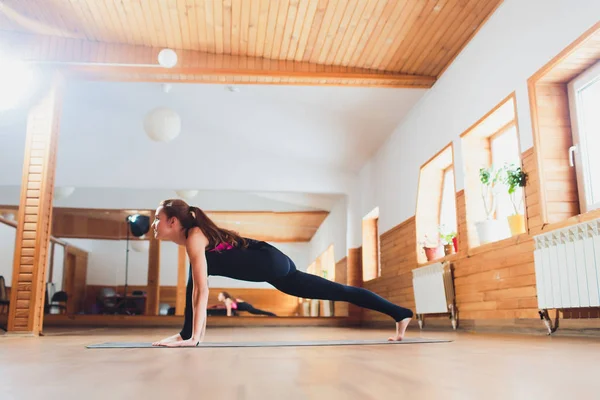 Deportiva hermosa joven practicando yoga, ejercitándose, haciendo alternativa fácil a Chaturanga Dandasana, media push-up, pose de ocho extremidades o oruga, Ashtanga Namaskara, estudio . — Foto de Stock