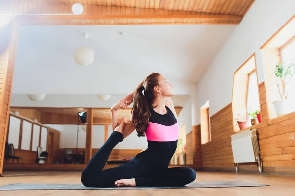 Porträt einer sportlich schönen blonden Frau in Sportbekleidung, die drinnen arbeitet und Variationen der Körperhaltung nach oben ausführt, Eka Pada ardha purvottanasana auf orangefarbener Matte, volle Länge. — Stockfoto