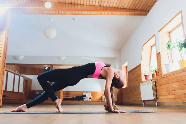 Junge Frau praktiziert Yoga, Stretching in Variation der Reverse-Table-Top-Übung, Bridge-Pose, Workout, trägt weiße Sportbekleidung, drinnen volle Länge. — Stockfoto