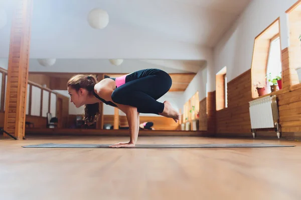 Joven mujer yogui atractiva practicando yoga, de pie en el ejercicio de Parsva Bakasana, Side Crane pose, haciendo ejercicio, usando ropa deportiva negra, estilo urbano fresco, larga duración, fondo de estudio . — Foto de Stock