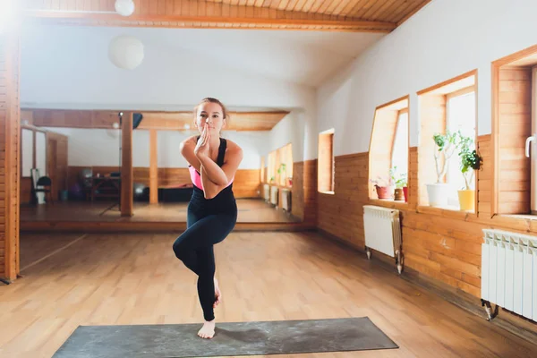 Joven mujer atractiva practicando yoga, de pie en el ejercicio de Águila, pose Garudasana, haciendo ejercicio, usando ropa deportiva, traje, interior de cuerpo entero, fondo de estudio . — Foto de Stock