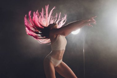 Kırmızı saçlı kutup dans kız egzersizleri ve siyah arka plan üzerinde duman pilon üzerinde pozlar.