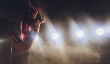 Işık ve duman ile karanlık iç genç ince kadın pole dans.