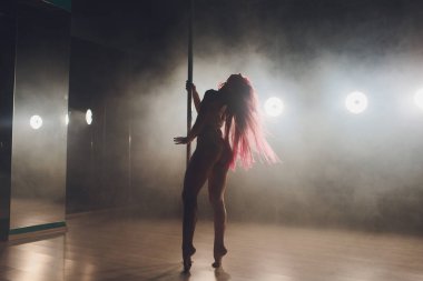 Işık ve duman ile karanlık iç genç ince kadın pole dans.