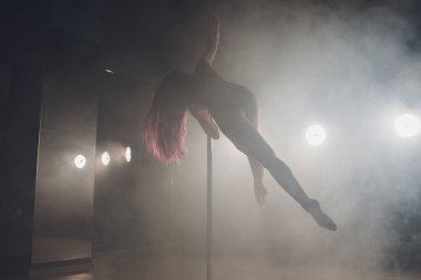 Işık ve duman ile karanlık iç genç ince kadın pole dans.
