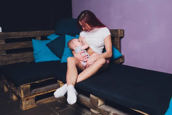 Mother breastfeeding baby in her arms at home. Beautiful mom Red hair breast feeding her newborn child. Young woman nursing and feeding baby. Concept of lactation infant. — Stock Photo, Image