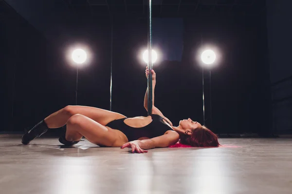 Ung pole dans kvinna på svart vägg bakgrund med flare effekt. Idrott förkroppsligar i mörker studion. — Stockfoto