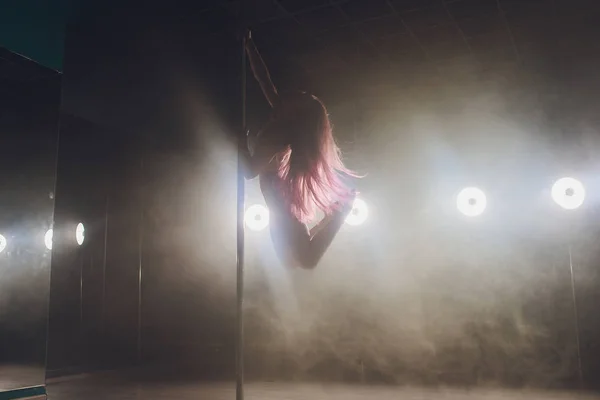 Jeune femme mince pole dance dans l'intérieur sombre avec des lumières et de la fumée . — Photo