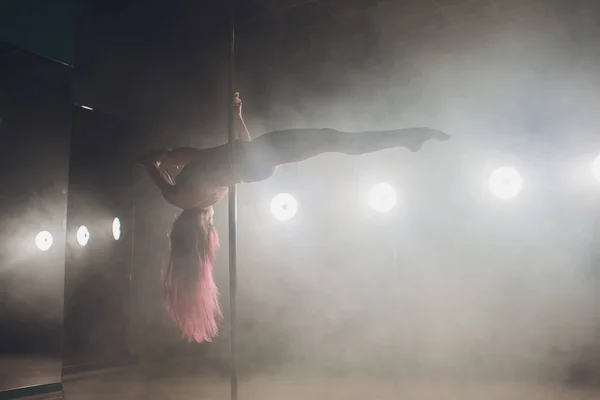 Giovane donna sottile pole dance in interni scuri con luci e fumo . — Foto Stock